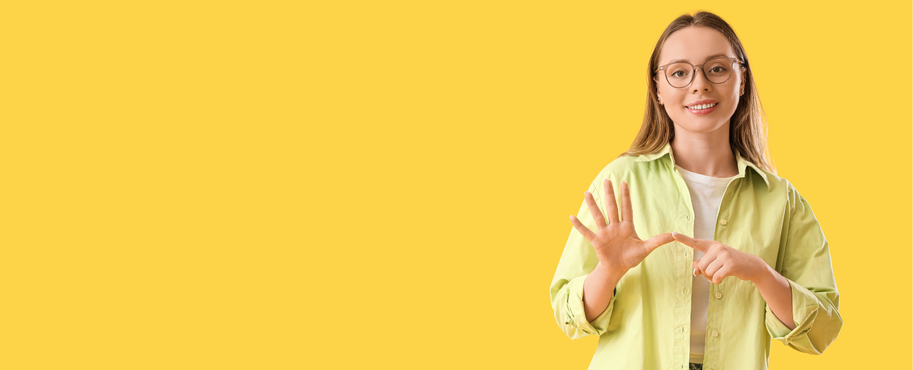 Woman signing letter A in NZSL on a yellow background.